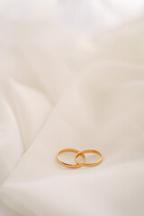 wedding rings on a white translucent chintz fabric, wedding gold rings lie on a white veil or tulle, free space for text