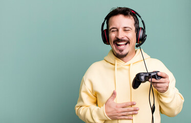 adult man laughing out loud at some hilarious joke with headset and a control. gamer concept