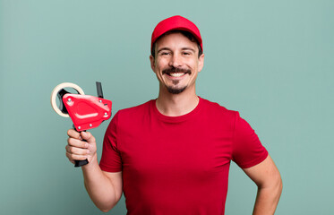 adult man smiling happily with a hand on hip and confident. deliveryman packer concept
