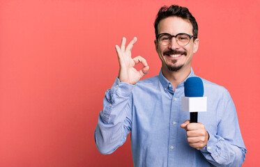 adult man feeling happy, showing approval with okay gesture with a microphone. presenter or...