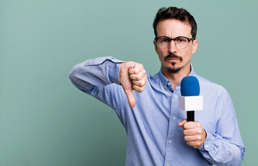 adult man feeling cross,showing thumbs down with a microphone. presenter or journalist concept