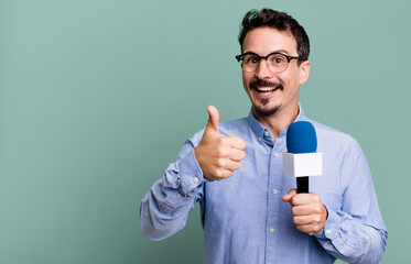adult man feeling proud,smiling positively with thumbs up with a microphone. presenter or...