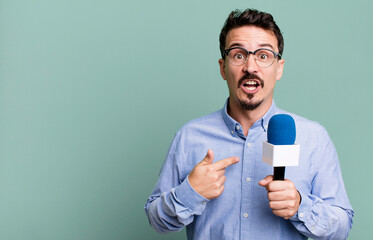 adult man looking shocked and surprised with mouth wide open, pointing to self with a microphone....