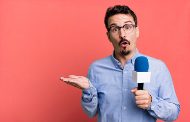 adult man looking surprised and shocked, with jaw dropped holding an object with a microphone....