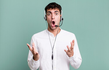 adult man amazed, shocked and astonished with an unbelievable surprise with headset. telemarketer...