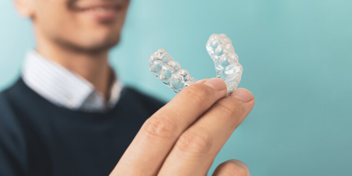 A man posing with orthodontic resin splints. Alteration of invisible teeth. The mobile orthodontic device for dental correction is in the foreground,Copyspace