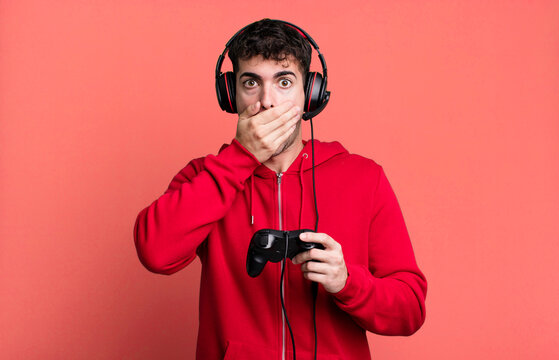 adult man covering mouth with hands with a shocked with headset and a controller. gamer concept