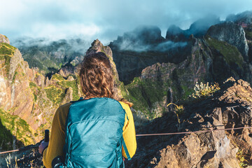 Woman enjoying the mountain scenery of Pico Ruivo from a viewing platform with very steep cliff in...