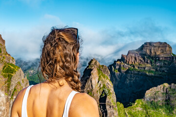 Woman enjoying the mountain scenery of Pico Ruivo from a viewing platform with very steep cliff in...