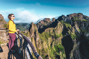 Woman enjoying the mountain scenery of Pico Ruivo from a viewing platform with very steep cliff in...