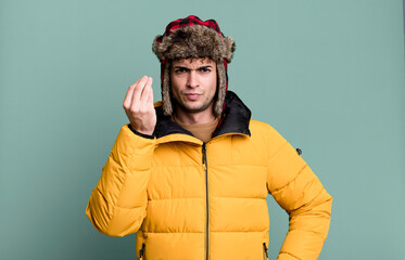 adult man making capice or money gesture, telling you to pay wearing anorak. winter and cold concept © kues1