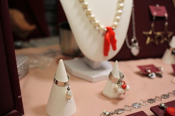 Bijouterie on a red background. Decorations at the fair. Handmade products. Hobby. Fashionable accessories. Earrings and necklace