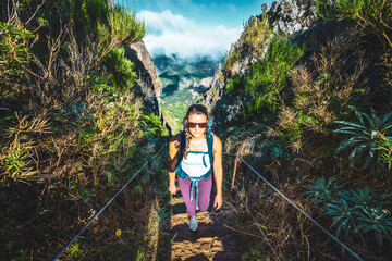 Woman with backpack hiking up steep stairs along scenic hike trail to Pico Ruivo in the morning....