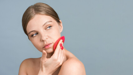 A young caucasian woman is doing a facial massage using face scrubber