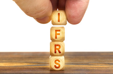 A man puts wooden cubes on the table with the inscription - IFRS