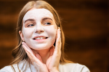 A young caucasian smiling woman is making a face mask
