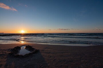 Zachód słońca nad morzem Bałtyckim z rzeźbą na plaży 