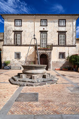 Fototapeta na wymiar A stone well and a historic tenement house in Gradoli