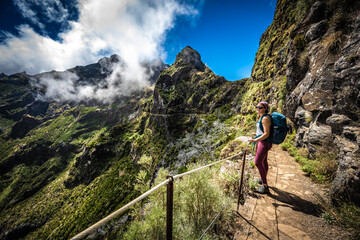 Hiker with backpack enjoying the view along very scenic hike trail to Pico do Ariero in the afternoon. Verade do Pico Ruivo, Madeira Island, Portugal, Europe.
