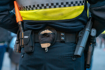 A police officer's belt with handcuffs, pepper spray, walkie talkie and a gun