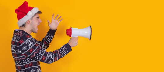 young man with santa claus hat isolated shouting with loudspeaker