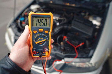 Checking car battery with digital multimeter. Check car battery using voltmeter. Man check up...
