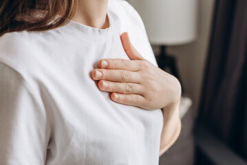 Close-up of ill young caucasian female putting hand on chest, feels discomfort. Having pain in chest, Gastroesophageal Reflux Disease have frequent belching. Healthcare medical and people concept - obrazy, fototapety, plakaty