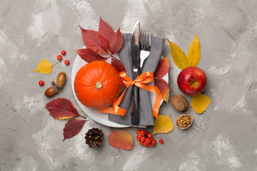 Plate with cutlery, napkin and autumn decor on wooden background, top view. Thanksgiving table setting.