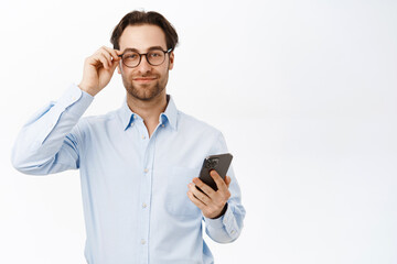 Handsome smiling office worker, businessman in glasses standing with mobile phone, advertisement of an office application, white background