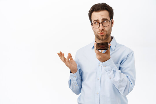 Handsome businessman recording voice message. Male entrepreneur translating voice on smartphone app, standing over white background