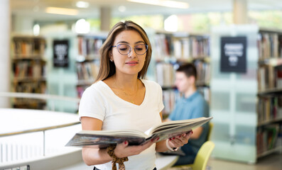 View on a young Latina student holding books in the library