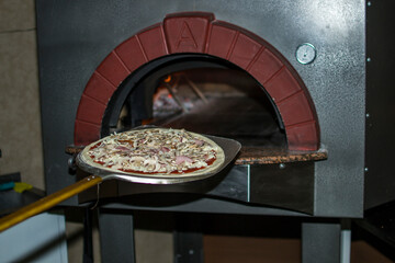 Pizza near the stone stove with fire. Background of a traditional pizzeria restaurant with a fire...