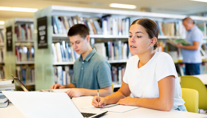 View on young european students studying together with a laptop in library