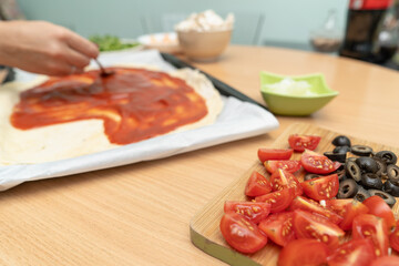 Cooking homemade pizza with tomatoes and olives.