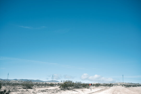 Dirt Road in the Mojave Desert with power lines running across the background and mountains in the horizon