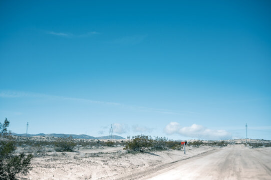 Dirt Road in the Mojave Desert with power lines running across the background and mountains in the horizon