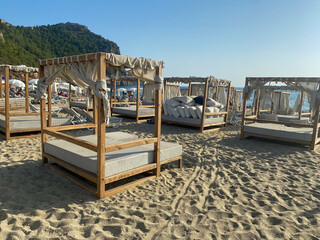 Many sunbeds and canopies on a sandy beach with a mountain and sea in a warm tropical oriental country southern resort