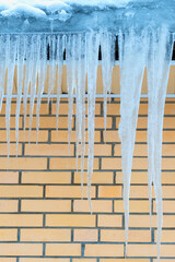 Sharp and dangerous ice icicles hang from roof in winter. Icicles hanging dangerously from roof.