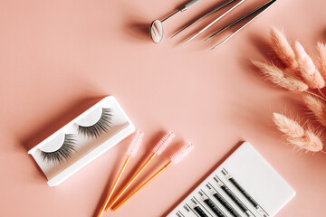 Tools for eyelash extension on trendy pastel pink background. False eyelashes, tweezers and brushes. Beauty shop. Makeup cosmetics. Top view, flat lay