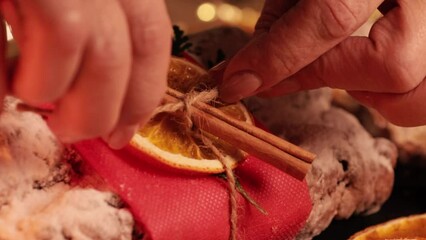 Close-up woman's hand decorate Christmas Stollen. Traditional christmas german dessert. Cake with nuts, raisins with marzipan and dried fruit on cutting board. Baking for xmas