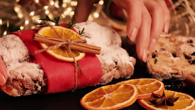 Christmas Stollen in baker's female hands close up. Traditional christmas german dessert. Cake with nuts, raisins with marzipan and dried fruit on cutting board. Baking for xmas