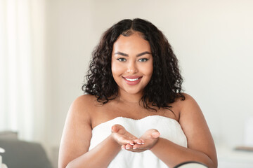Attractive black chubby woman demonstrating something on empty palms, showing invisible object