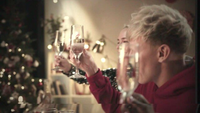 Retro tape VHS effect, home camera video, Friends celebrating new year, sitting at dining table. International young people clinking glasses with champagne and drinking, toasting.