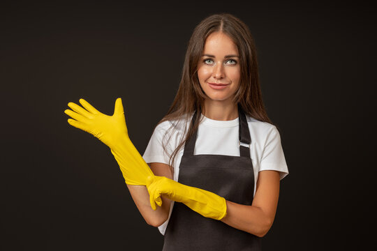 girl housewife in an apron and rubber gloves on a black background
