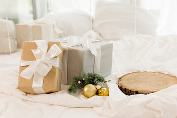 Christmas gifts on the bed on a white sheet. Spruce branch. Cozy morning.