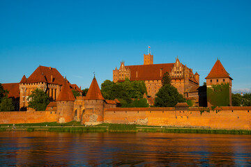 Naklejka na ściany i meble Marienburg Castle the largest medieval brick castle in the world in the city of Malbork at sunset