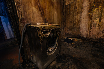 Burnt house interior. Fused remains of furniture and washing machine.