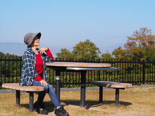 自然の中でベンチに座わる高齢日本人女性