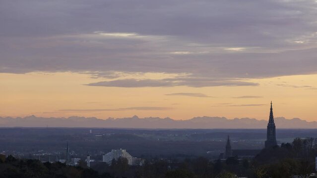 Time lapse shot of Ulm minster and the landscape around Ulm while a colorful dusk with Alps in background due to foehn effect