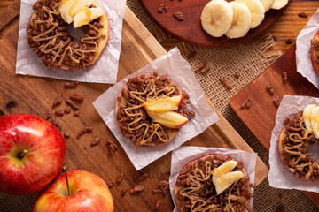 Creative party snack for holidays. Apple rounds with peanut butter, caramel and chocolate flavor puffed rice topping with banana slices. Funny appetizer for kids and adults.